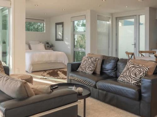 un soggiorno con divano in pelle e letto di Seascapes Waterfront 2 a Paraparaumu