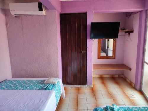 a small room with a bed and a tv at Hotel Casa Lucina in Zihuatanejo