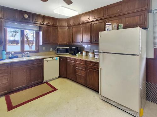 Una cocina con gabinetes de madera y un refrigerador blanco. en The Foxhole on East Lake Okoboji, en Spirit Lake