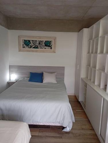 a bedroom with a large white bed and shelves at Eneas Flat luminoso con cochera in Pinamar