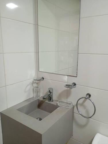 a white bathroom with a sink and a mirror at Eneas Flat luminoso con cochera in Pinamar