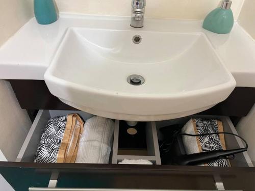a white sink in a bathroom with a shelf at Joli studio à l Anse Vata in Noumea