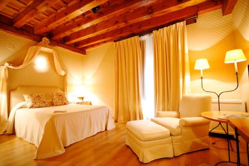 a bedroom with a bed and a chair in a room at El Hotel De La Villa in Pedraza-Segovia