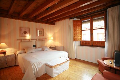 a bedroom with a large white bed and a couch at El Hotel De La Villa in Pedraza-Segovia