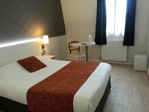 a hotel room with a bed and a table at Contact Hôtel du Cerf in Château-Gontier