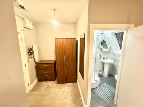 a bathroom with a wooden cabinet and a sink at Modern En-Suite Rooms by Finsbury Park Station 8 mins to King's Cross by Tube in London