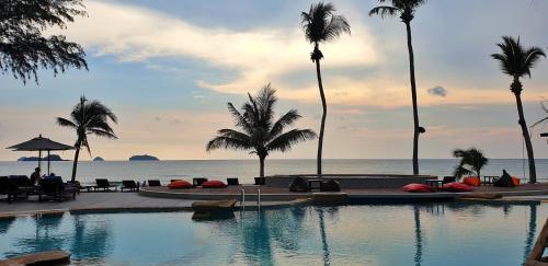 a swimming pool next to the ocean with palm trees at Klong Prao Resort in Ko Chang