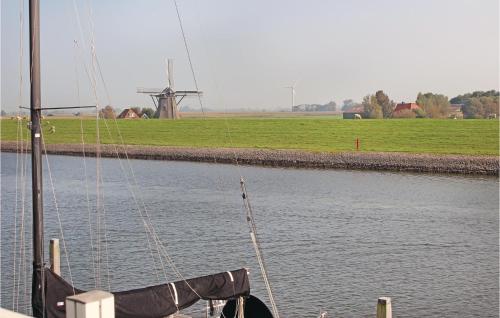 a boat in the water with a windmill in the background at 3 Bedroom Pet Friendly Home In Workum in Workum
