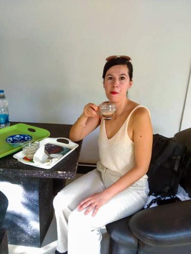 a woman sitting on a chair drinking from a glass at Lake Side Resort in Kekirawa