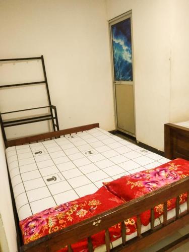 a bedroom with a bed with a red blanket on it at Lake Side Resort in Kekirawa