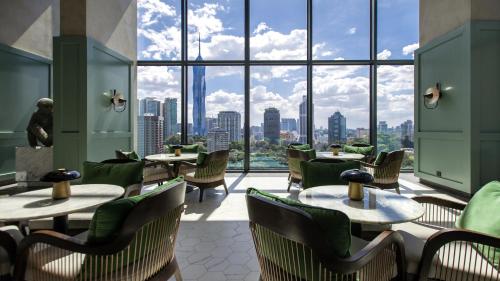 a restaurant with tables and chairs and large windows at Hotel Indigo Kuala Lumpur on the Park by IHG in Kuala Lumpur