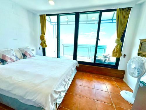 a bedroom with a white bed and a large window at Rockhand Homestay in Eluan