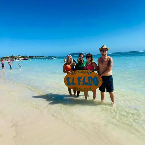 a group of people standing on a beach with a sign at Day Pass Todo Incluido El Faro Beach Club & Restaurant Solo Experiencia no incluye alojamiento - 85 USD por persona in Mahahual