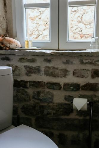 a bathroom with a toilet and two windows at City Rooms Šibenik in Šibenik