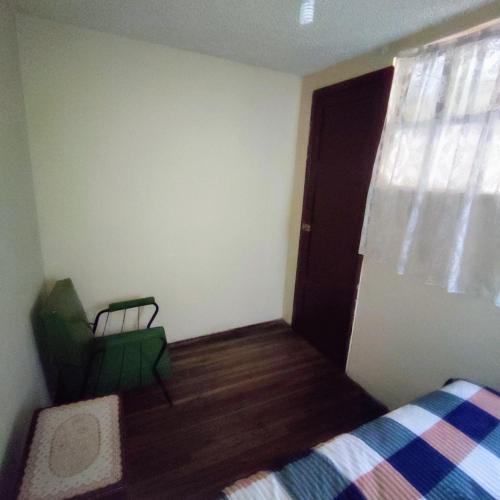 a bedroom with a bed and a green chair at Conexión Urbana en el centro de Ambato in Ambato