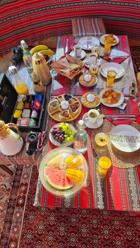 a table with plates of food and drinks on it at Starwatching Private Camp in Ḩawīyah