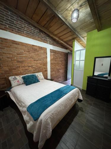 a bedroom with a bed and a brick wall at Rincón del Ángel in Zacatlán