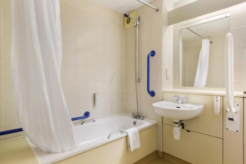 W łazience znajduje się wanna, umywalka i prysznic. w obiekcie Ramada London South Mimms w mieście Potters Bar