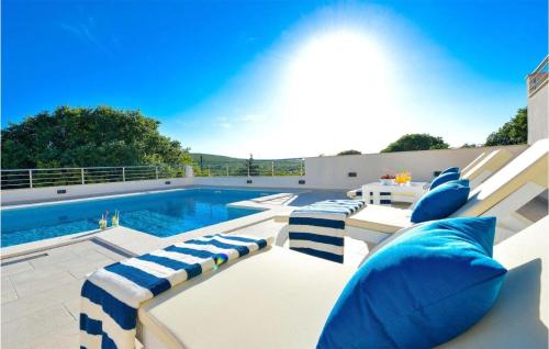 a swimming pool with blue and white lounge chairs next to a pool at Cozy Home In Unesic With Sauna in Unešić