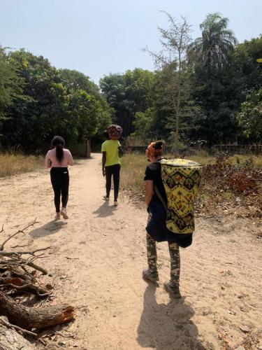 three women walking down a dirt road with baskets on their heads at Guest House La Maison des Amis in Abene