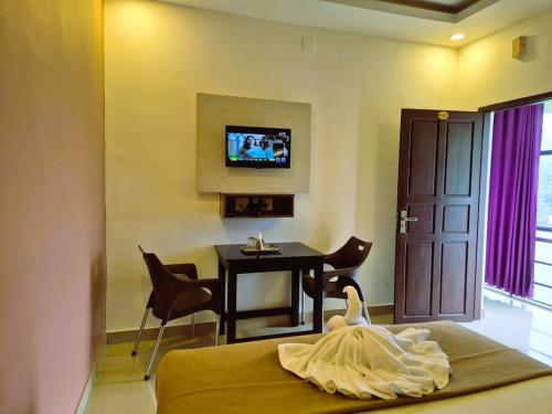 a room with a bedroom with a table and a tv at Alfa Inn in Nedumbassery