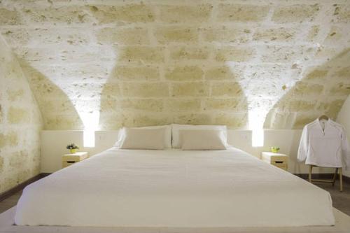 - une chambre avec un grand lit blanc et 2 tables dans l'établissement Il Vento dei Sassi, à Matera