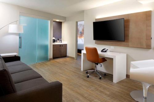 a living room with a desk and a tv on a wall at Cambria Hotel Phoenix Chandler - Fashion Center in Chandler