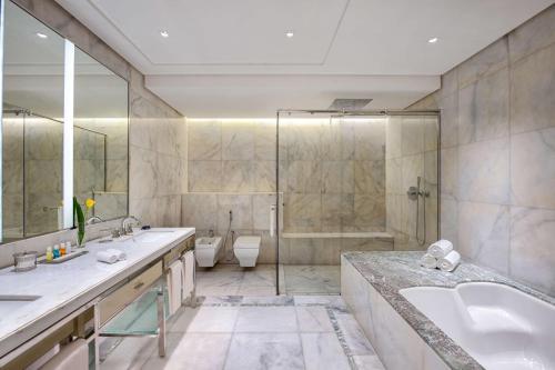 a bathroom with two sinks and a tub and a shower at The Hotel Galleria Jeddah, Curio Collection by Hilton in Jeddah