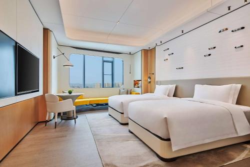 two beds in a hotel room with a flat screen tv at Wyndham Garden Nanjing Airport in Nanjing