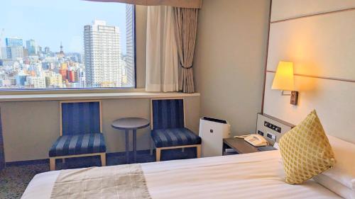 a hotel room with a bed and two chairs and a window at Premier Hotel Nakajima Park Sapporo in Sapporo