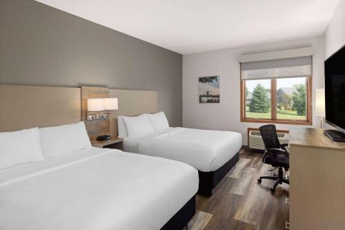 a hotel room with two beds and a desk at Links Bos Landen Hotel & Spa of Pella, Trademark by Wyndham in Pella