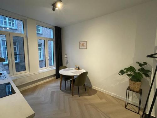 Un comedor con mesa y sillas y ventanas. en Stadsstudio op toplocatie, en Amberes