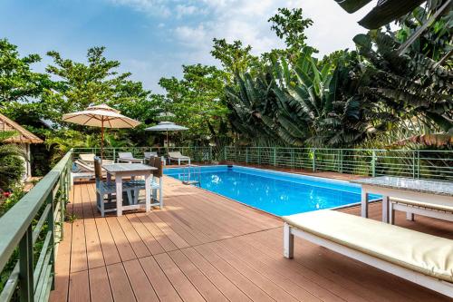 an outdoor deck with a swimming pool and an umbrella at Akasa Goa in Palolem