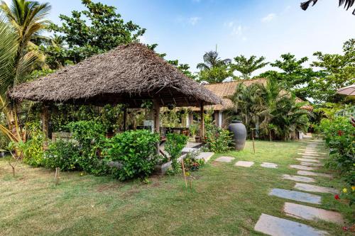 a house with a thatch roof and a grass at Akasa Goa in Palolem