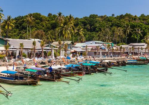 a group of boats sitting in the water on a beach at Phi Phi Ba Kao Bay Resort in Phi Phi Don