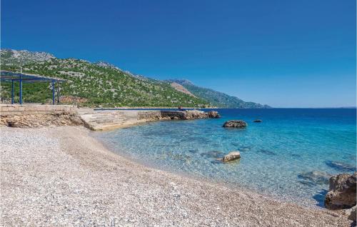a beach with rocks and the blue water at 2 Bedroom Gorgeous Home In Karlobag in Karlobag
