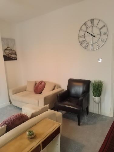 a living room with a couch and a clock on the wall at Spacious House, Near Haigh Woodland Park, Wifi, Parking in Leigh
