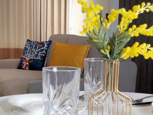 a table with two glass vases and yellow flowers on it at Continew Residence by HomeBrickz in Kuala Lumpur