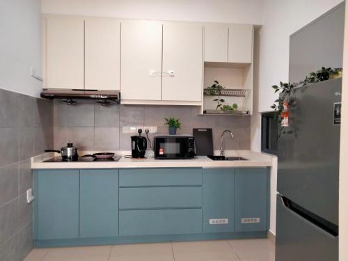 a kitchen with blue and white cabinets and a refrigerator at Continew Residence by HomeBrickz in Kuala Lumpur