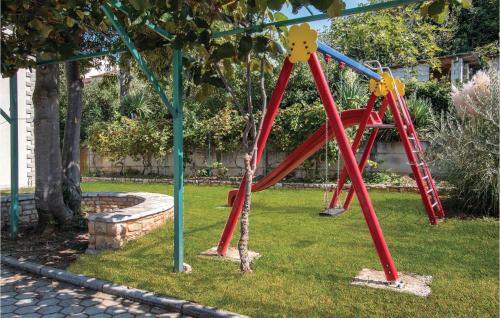 a playground with a red swing set in a yard at Beautiful Home In Liznjan With Sauna in Ližnjan