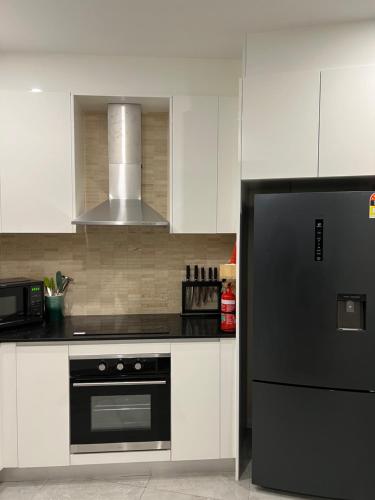 a kitchen with a black refrigerator and white cabinets at Guesthouse koonawarra in Dapto