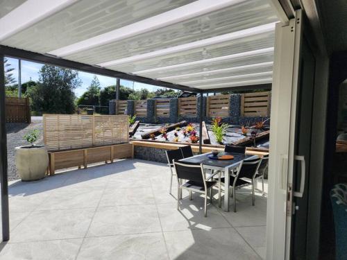 a patio with a table and chairs under a pergola at #40 Below in Waitarere