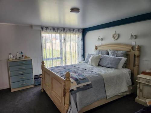 a bedroom with a large bed and a window at #40 Below in Waitarere