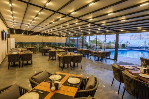 a restaurant with tables and chairs and a pool at Caddem Inn Hotel in Mağusa