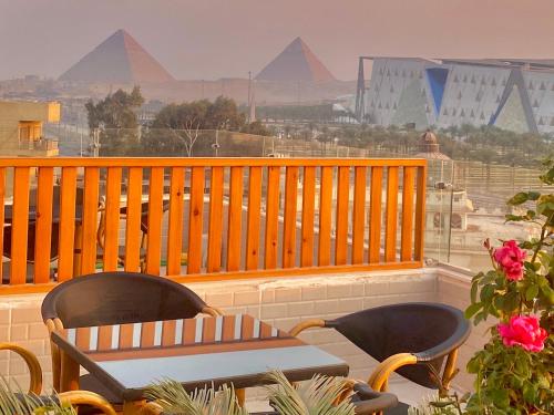 two chairs and a table on a balcony with pyramids at New Museum Guest House, Pyramids View in Cairo