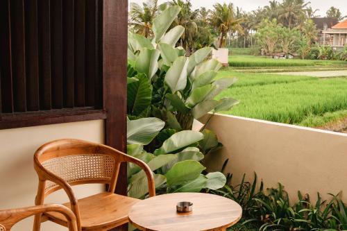 a table and chairs on a balcony with a rice field at Tut Winten a Tranquil Living Villa Ubud in Ubud