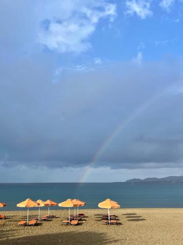 a row of umbrellas on a beach with a rainbow in the background at Pal Beach in Palaiochóra