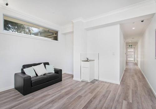 a living room with a black couch and a window at Sip and Dip - Woonona in Woonona