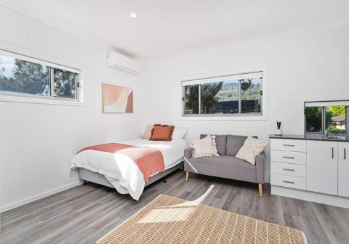 a bedroom with a bed and a couch and windows at Sip and Dip - Woonona in Woonona