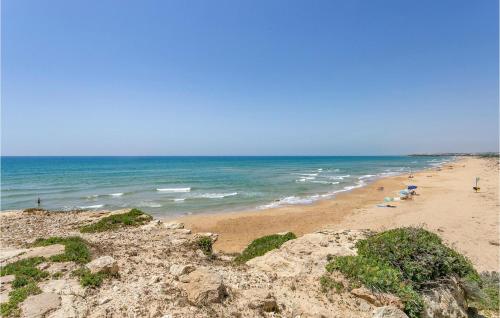 a beach with people and umbrellas and the ocean at Gorgeous Home In Comiso With Wifi in Comiso